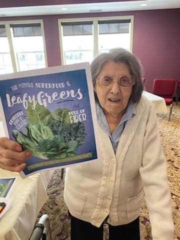 resident with leafy greens sign