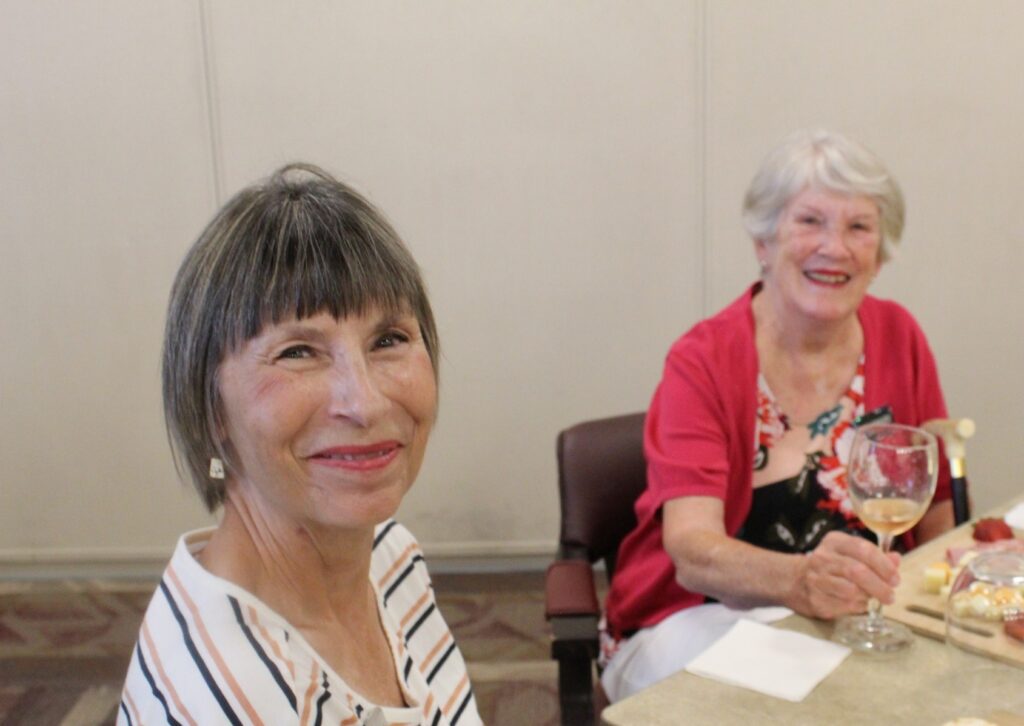 two senior residents eating a meal and drinking wine