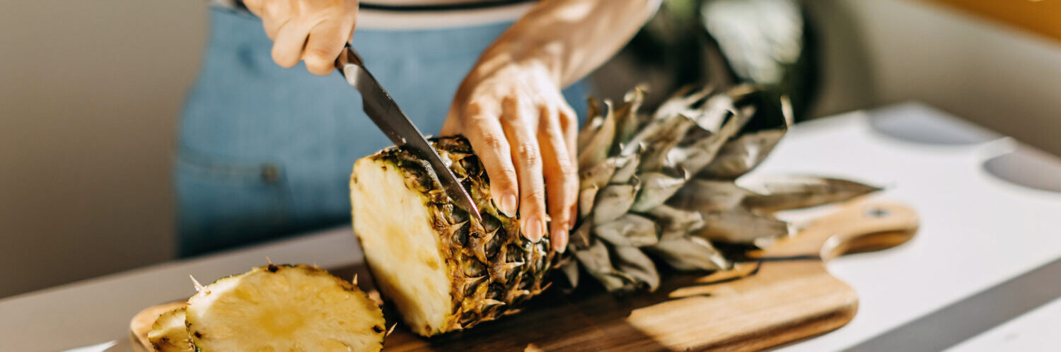 Woman cutting pineapple on desk