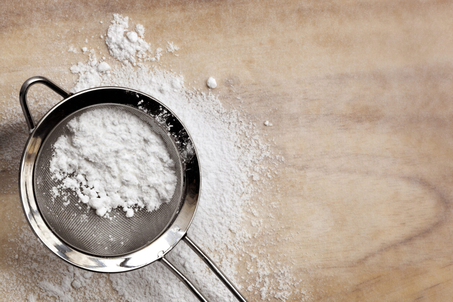 Icing or confectioner's sugar in sifter, over baking paper.