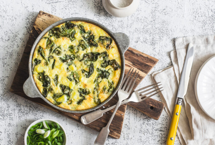 Potato and spinach tortilla in a pan on a light background. Delicious appetizer or snack, top view