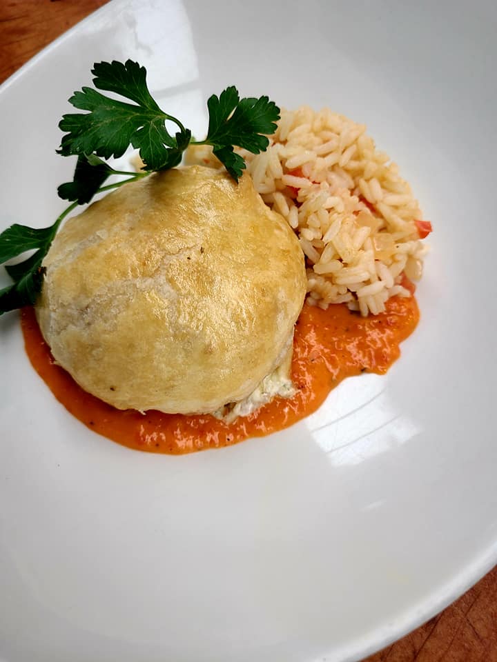 vegetable wellington made with squash, peppers, and onions served with rice and some sauce